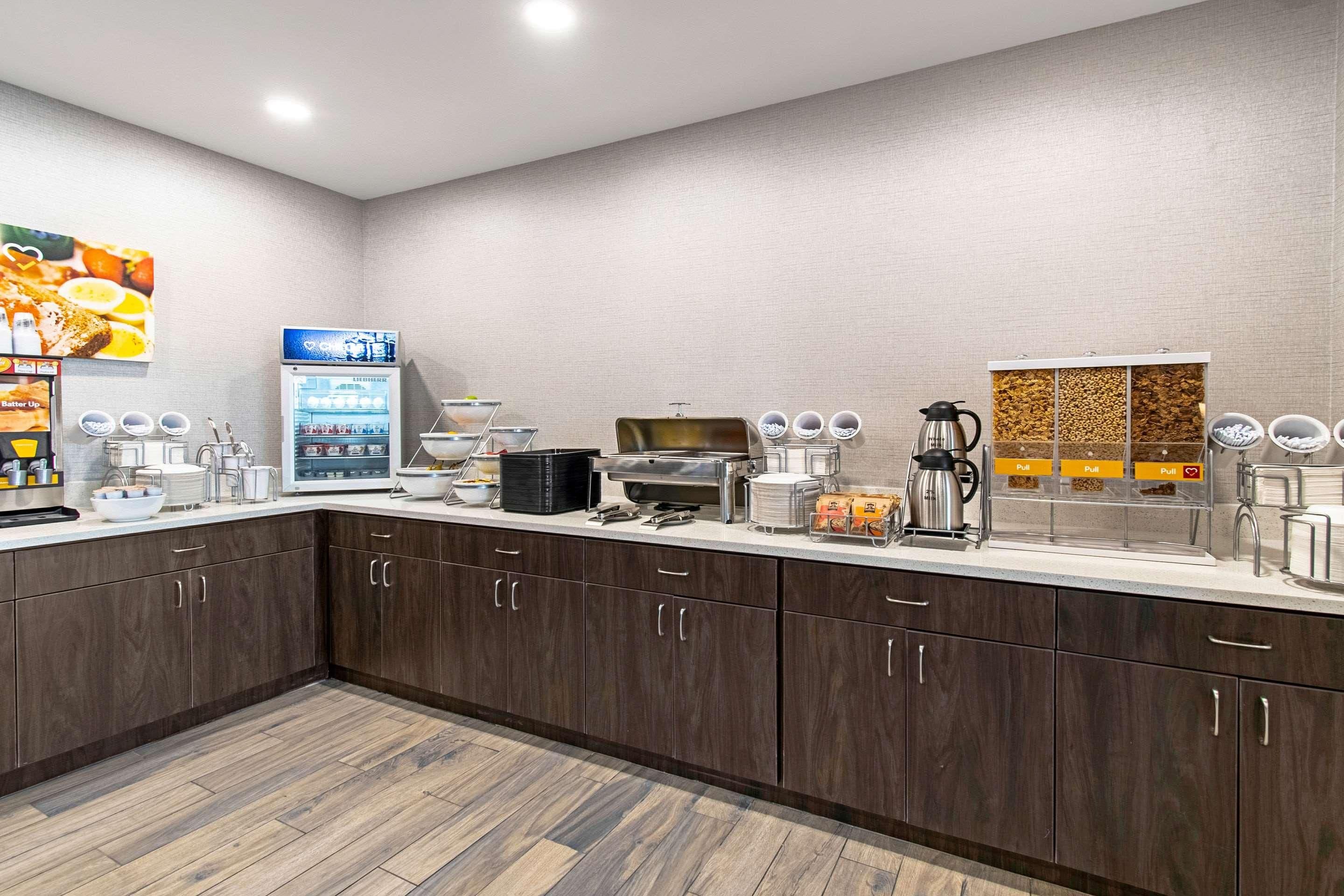 A modern kitchen with dark wood cabinets, a coffee machine, a refrigerator, and a buffet area with pull-out containers.