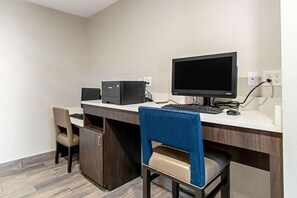 Ein Hotelzimmer mit Schreibtisch, Computer und zwei Stühlen.