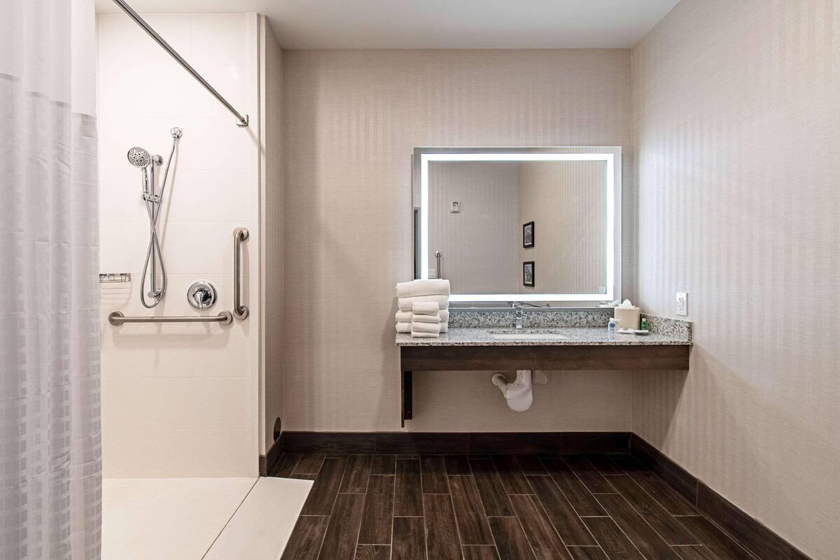 Une salle de bain moderne équipée d’une douche, d’un meuble-lavabo avec miroir et d’un porte-serviettes.