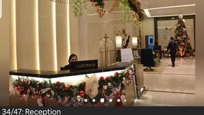 Un área de recepción con mostrador de conserjería, adornos navideños y un árbol de Navidad al fondo.