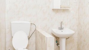 Een badkamer met toilet, wastafel en spiegel.
