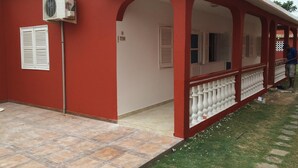 Een rood gebouw met een overdekte veranda, een witte balustrade en een betegeld terras.