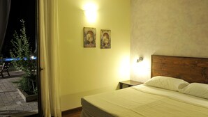 Quarto com cama, mesa de cabeceira e duas luminárias fixadas na parede.