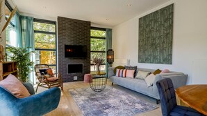 Un salon moderne doté d’une cheminée, de grandes fenêtres et d’un espace salon confortable.