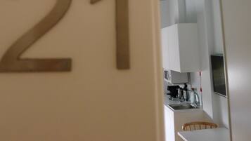 Habitación número 21, con una cocina visible a través de una puerta abierta, que incluye armarios y una estufa.