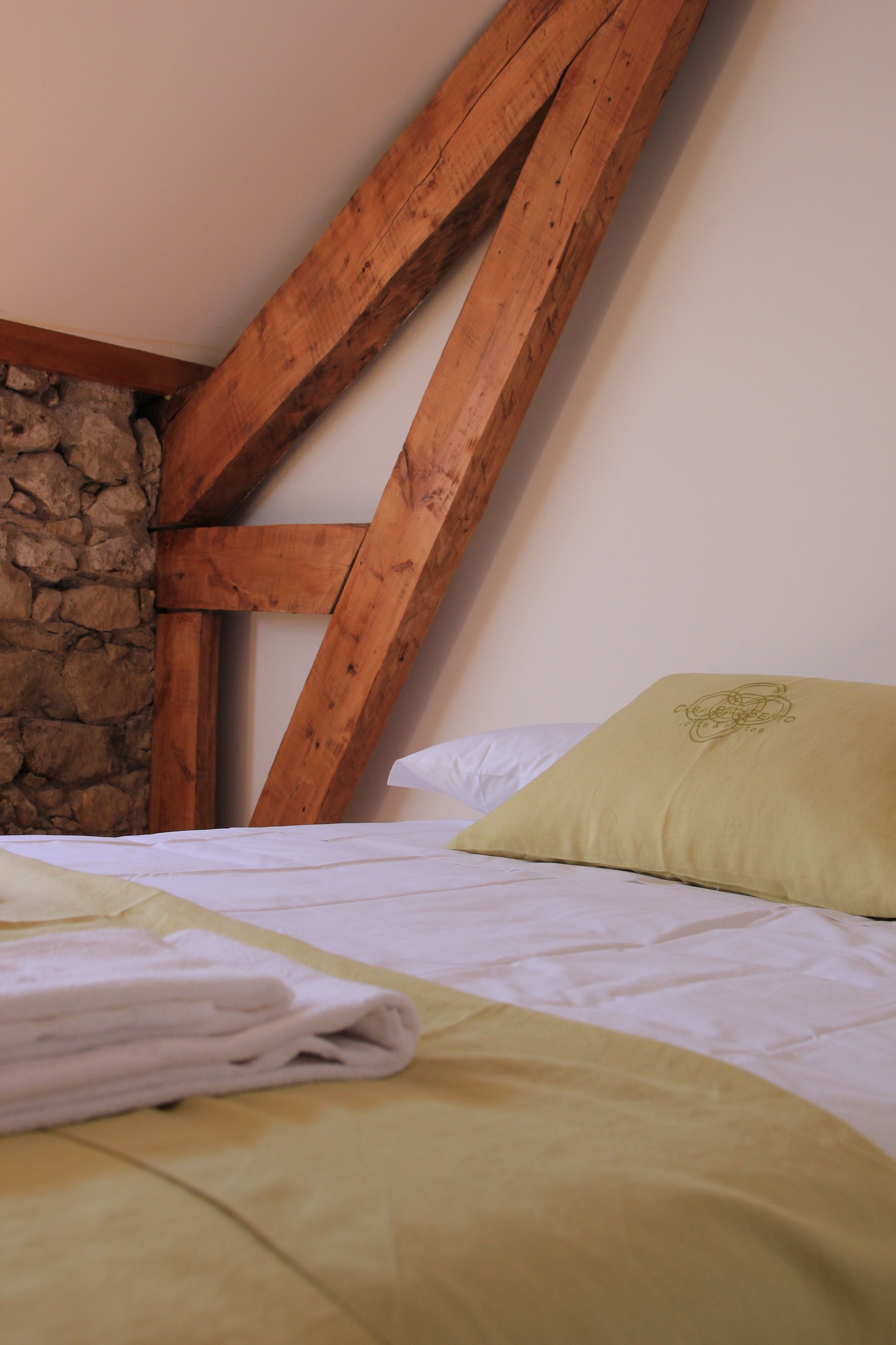 A room with a bed, a stone wall, and wooden beams.
