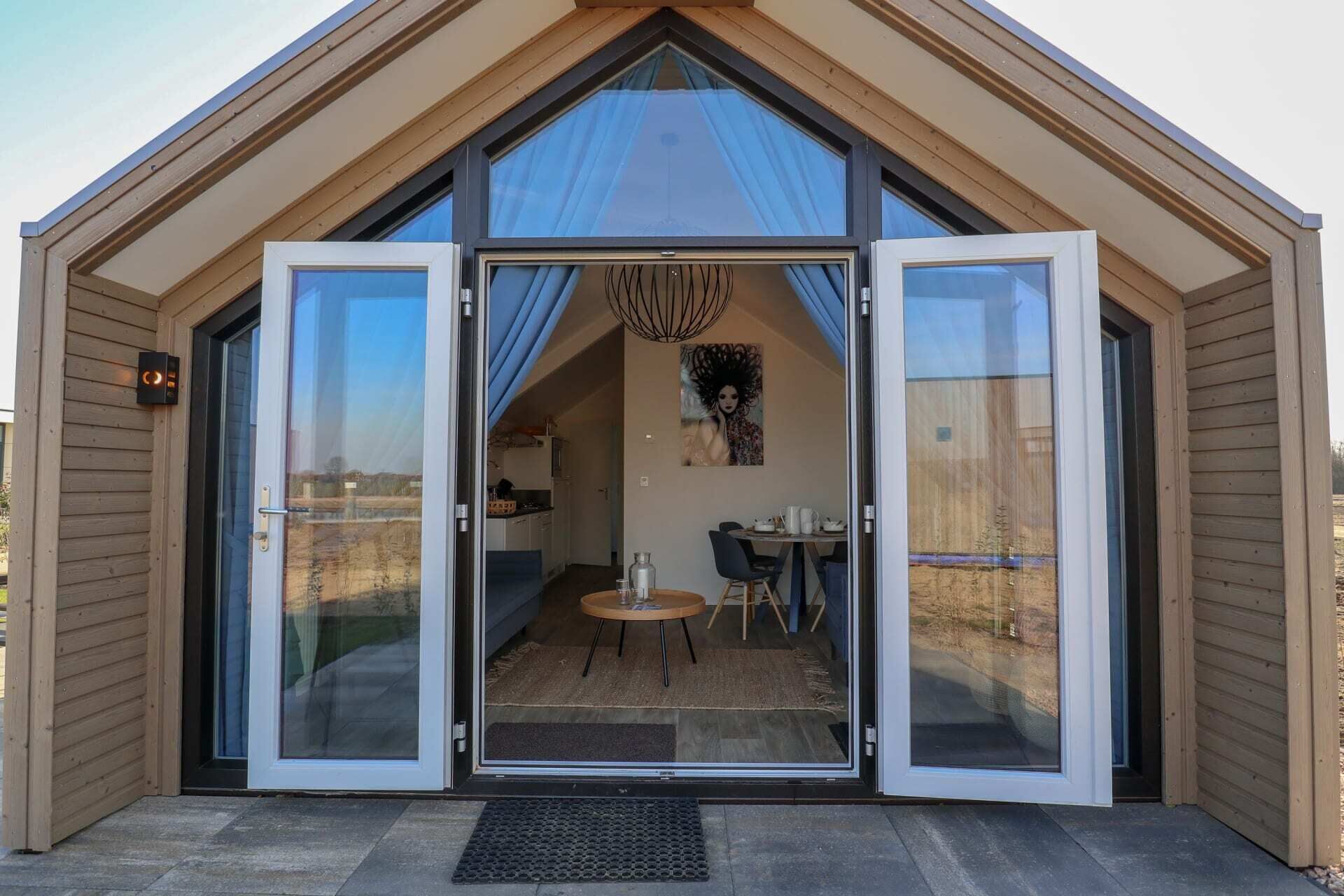 Uma casa moderna, térrea, com uma ampla porta de vidro deslizante que dá acesso a uma sala de jantar com mesa e cadeiras.