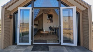 A modern, single-story house with a large sliding glass door entrance leading to a dining area with a table and chairs.