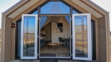 Uma casa moderna, térrea, com uma ampla porta de vidro deslizante que dá acesso a uma sala de jantar com mesa e cadeiras.