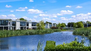 A riverside view with modern buildings, a bridge, and lush greenery. - EuroParcs Bad Hulckesteijn (Nijkerk)