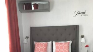 A bed with a grey headboard, two pink patterned pillows, and a red throw blanket. - Chandelier 302 (Ponce)