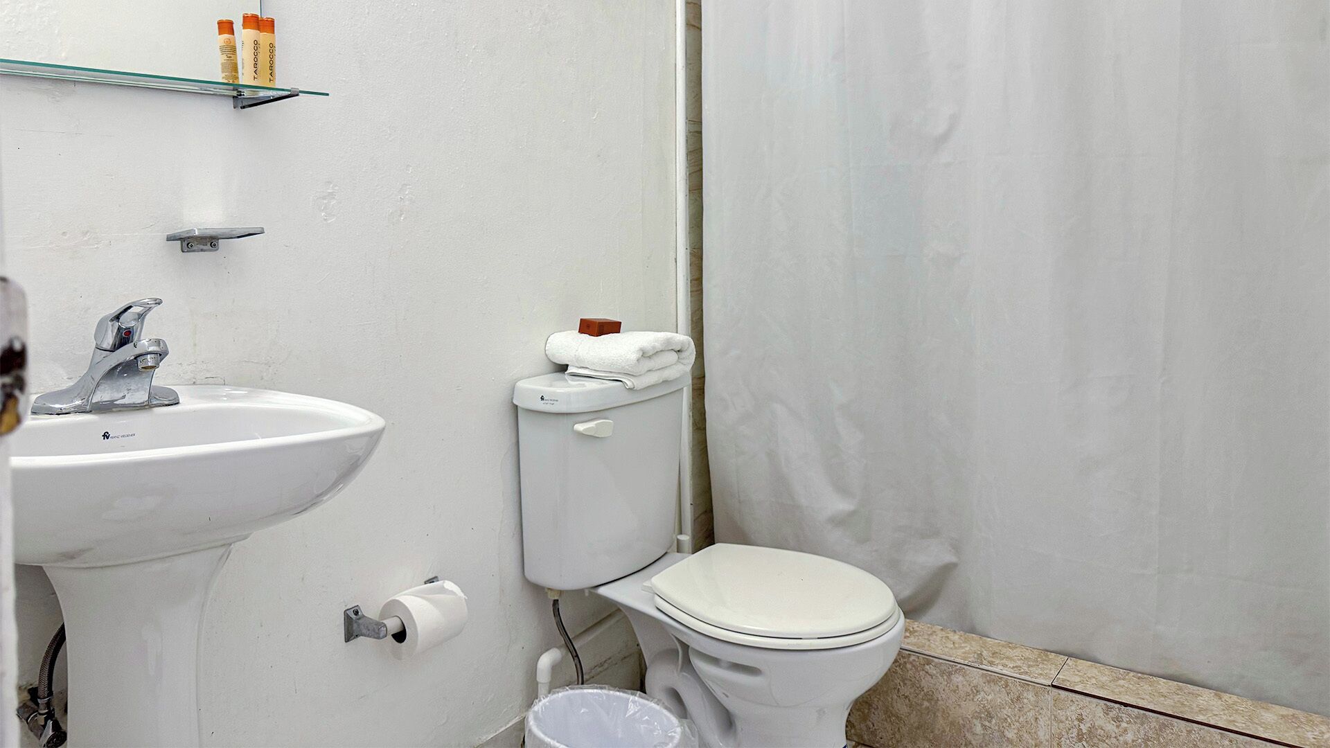 A bathroom with a white sink, a toilet, and a shower curtain.