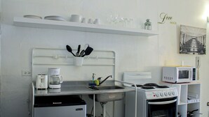A compact kitchenette with a stove, microwave, coffee maker, and a small sink.