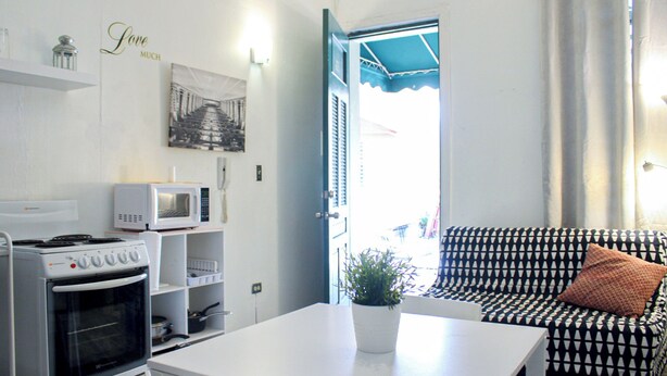 A compact living space with a kitchenette, a sofa, and a dining table.