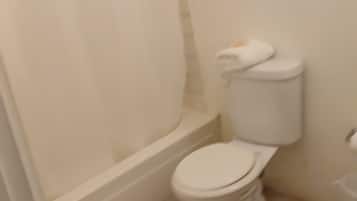 A small, clean bathroom with a toilet, a shower curtain, and a tiled floor.