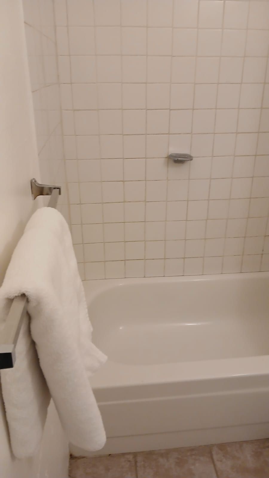 Une salle de bain avec une baignoire, des murs carrelés et un porte-serviettes.