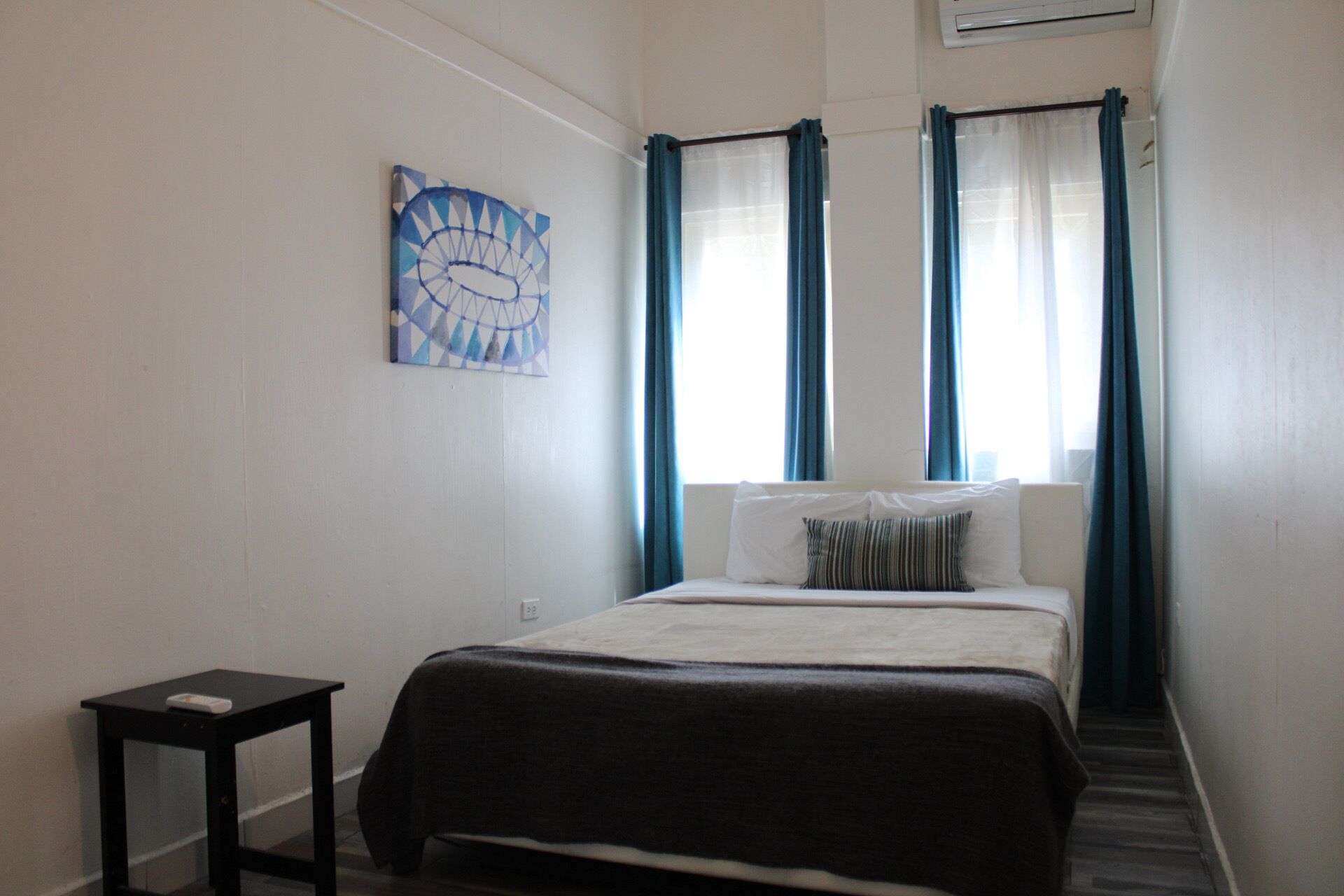 A bedroom with a bed, a small table, and a wall-mounted artwork.