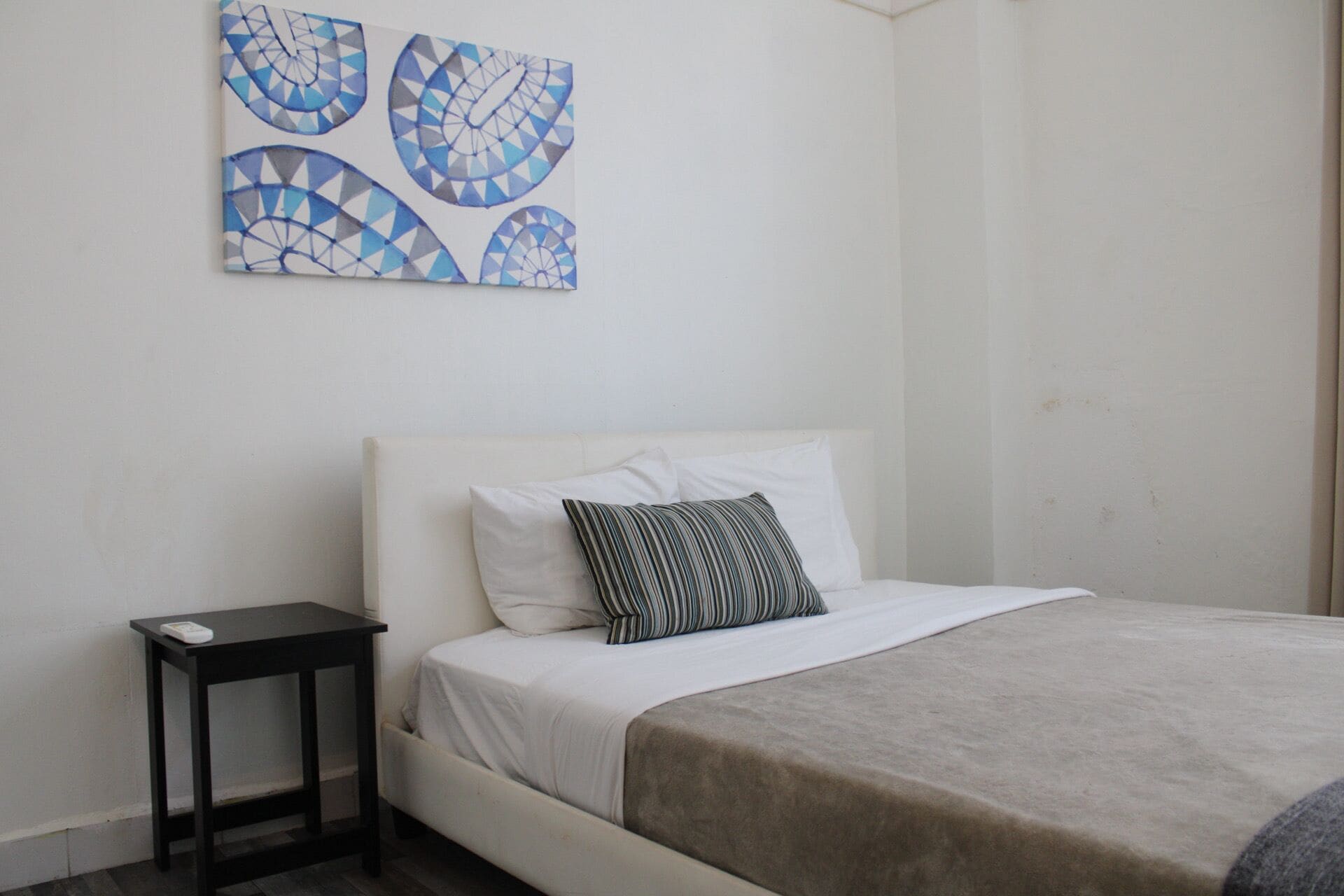 Une chambre à coucher comprenant un lit, une table de chevet et une œuvre d’art abstraite accrochée au mur.