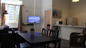 Un salon moderne doté d’un téléviseur à écran plat, d’une table à manger et d’un coin cuisine équipé d’un four à micro-ondes.