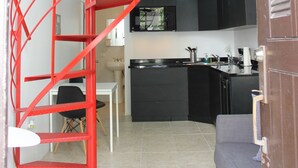Una cucina moderna con mobili neri, un divano grigio e una scala a chiocciola rossa.
