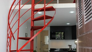 Un interno moderno con una scala a chiocciola rossa, una zona cucina e un'area pranzo.