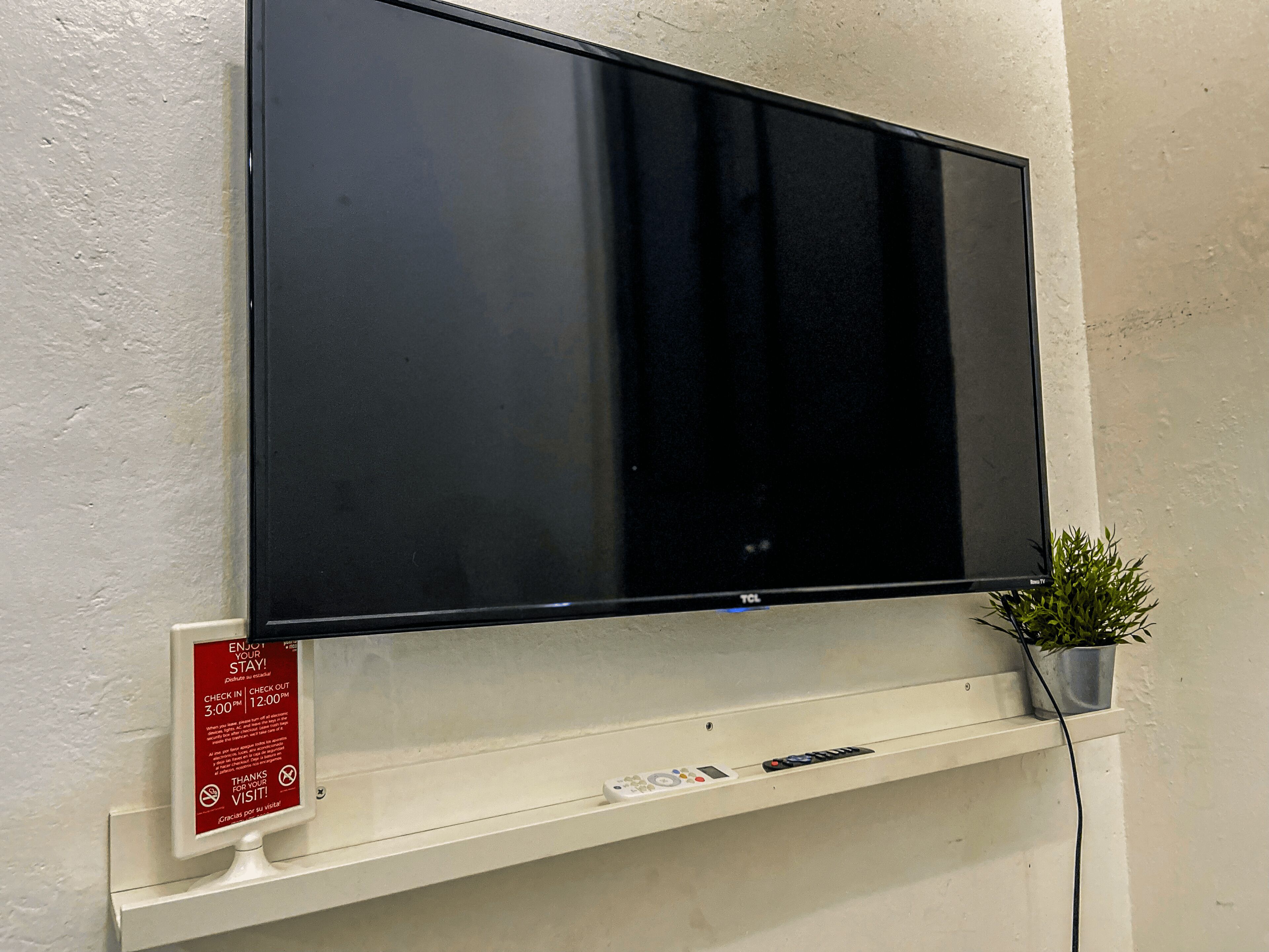 Een flatscreen-tv bevestigd aan een muur, met een bedieningspaneel eronder.