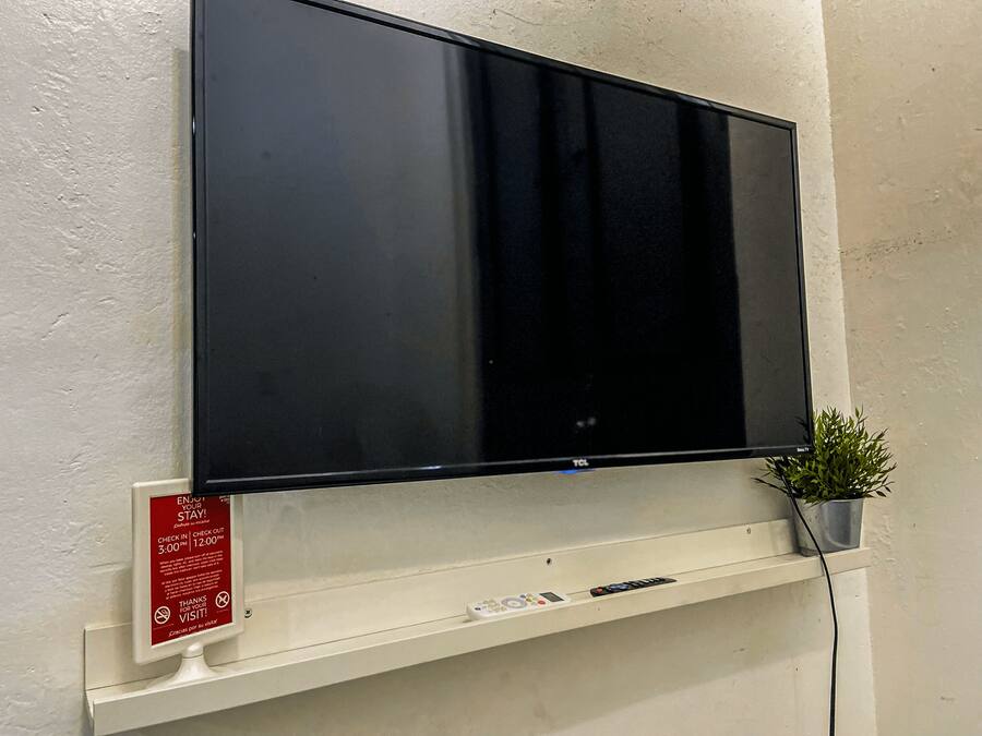 A flat-screen TV mounted on a wall with a control panel below it.