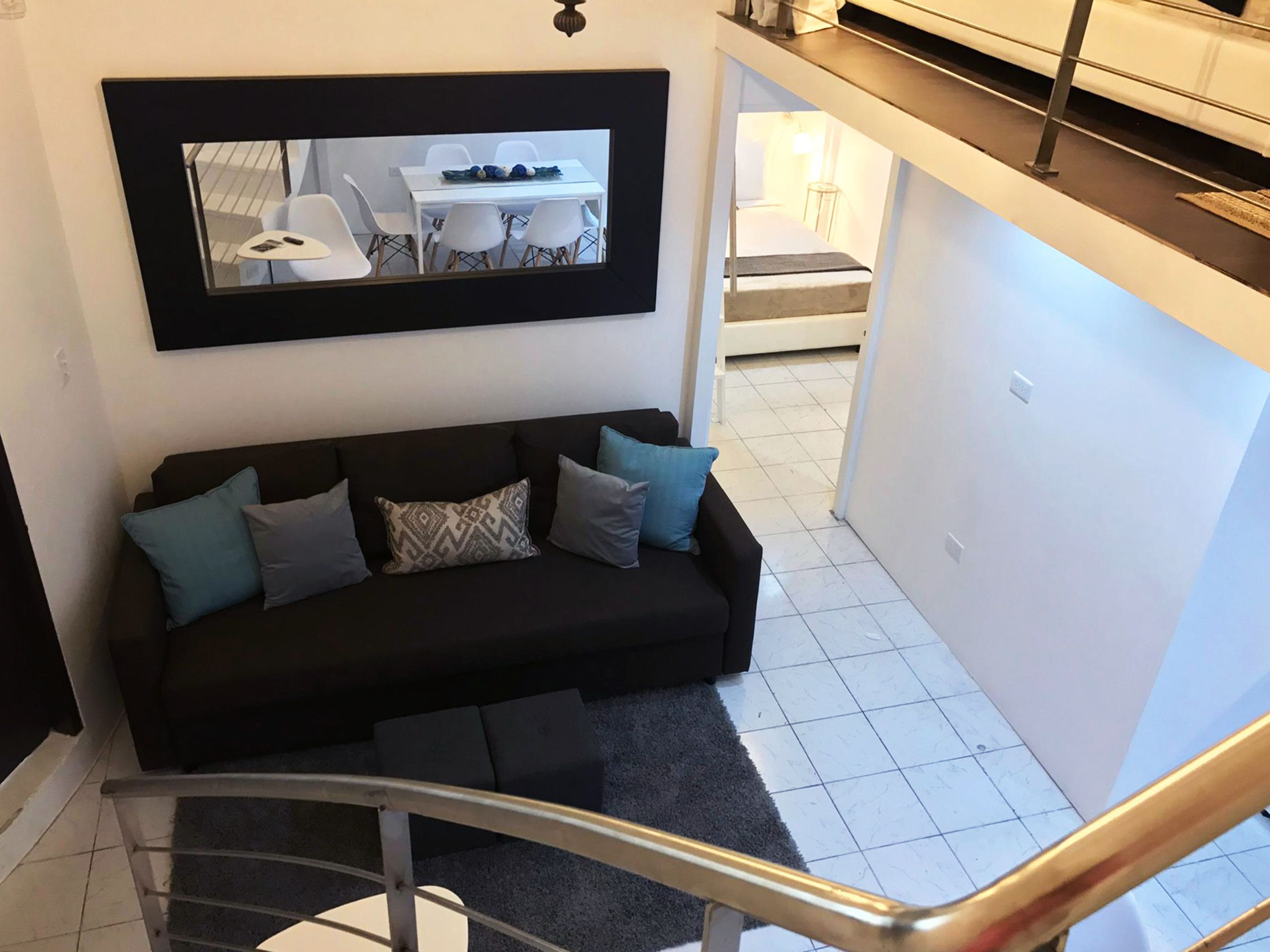A modern living room with a black sofa, a coffee table, and a framed picture on the wall.