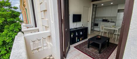 A balcony with a checkered floor, a black table, and a red rug.