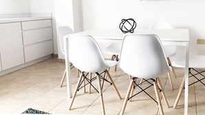 A modern kitchen with white cabinets and a microwave, a dining area with a white table and chairs, and a blackboard on the wall. - Boulevard 101 (Mayagüez)