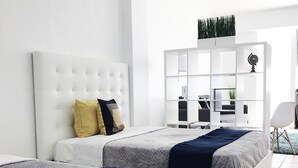 A modern bedroom with two beds, a white headboard, and a large window. - Boulevard 102 (Mayagüez)