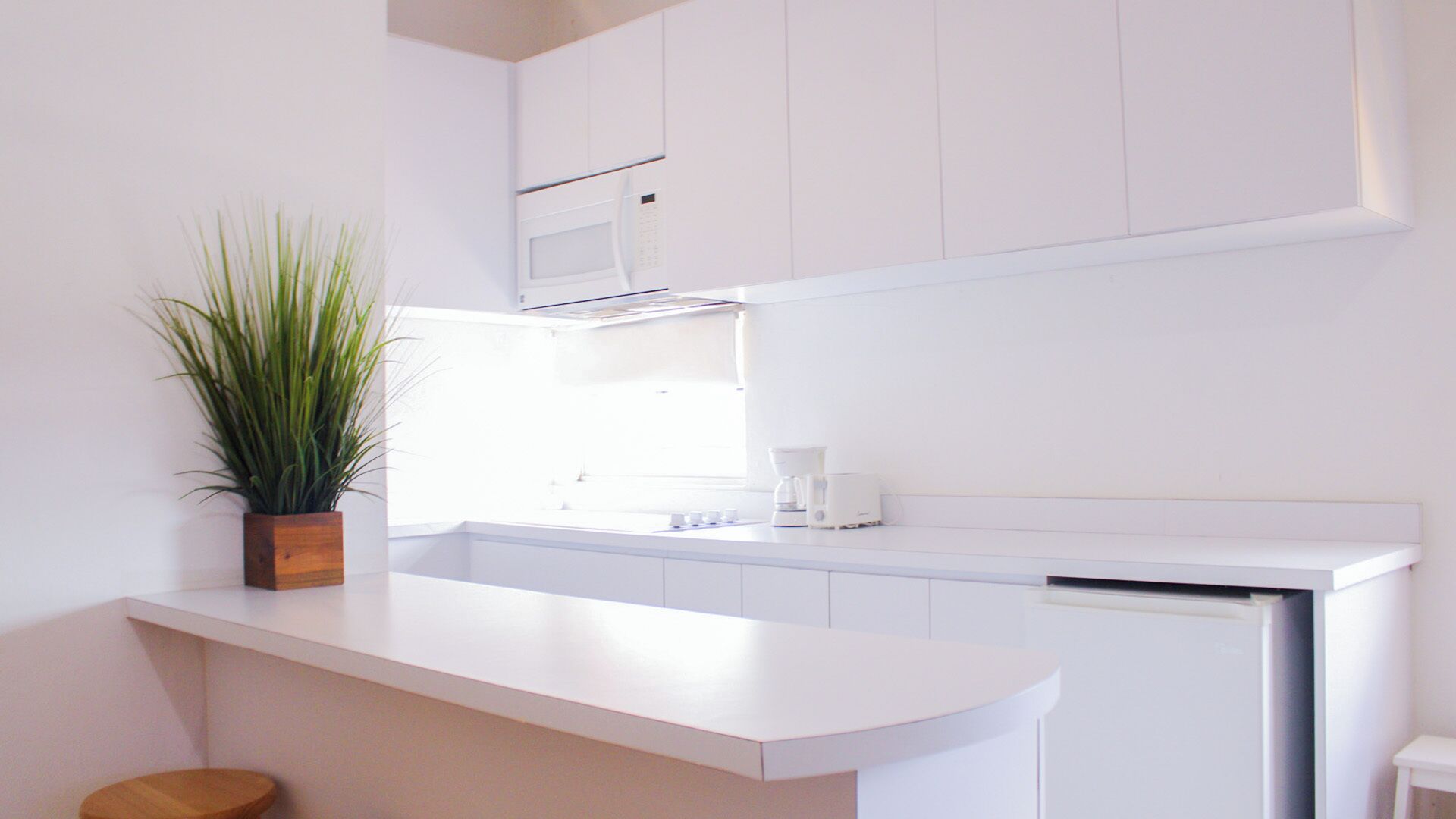 A modern kitchen with white cabinetry, a built-in microwave, and a coffee maker on the counter.