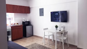 Un espace de vie compact comprenant une kitchenette, un coin repas avec télévision et un ventilateur de plafond.