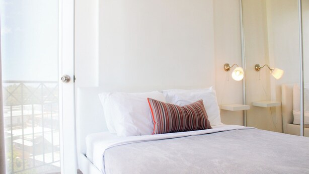 Une chambre d’hôtel avec un lit, une fenêtre et un luminaire fixé au mur.