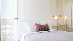 Habitación de hotel con cama, ventana y lámpara fijada a la pared.