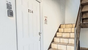 A white door with the number 204, a QR code, and a caution sign. - Boulevard 204 (Mayagüez)