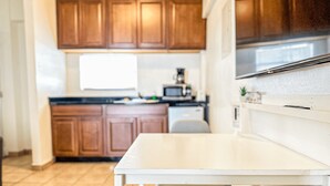 A kitchen with wooden cabinets, a white countertop, and a stainless steel range hood. - Boulevard 204 (Mayagüez)