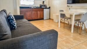A compact living space with a sofa, a small kitchen area, and a dining table. - Boulevard 204 (Mayagüez)
