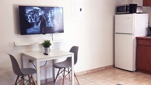 A compact living space with a dining table, two chairs, a television, a refrigerator, and a microwave. - Boulevard 205 (Mayagüez)