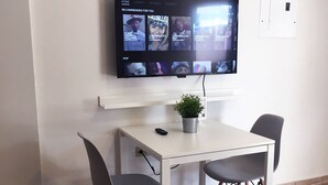 A modern room with a white table and two chairs, a flat-screen TV mounted on the wall, and a potted plant on the table. - Boulevard 205 (Mayagüez)