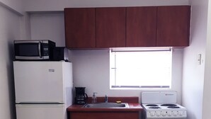 A compact kitchen with a refrigerator, microwave, coffee maker, sink, and stove. - Boulevard 205 (Mayagüez)