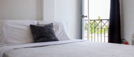 A hotel room with a bed, a window, and a view of the outdoors.