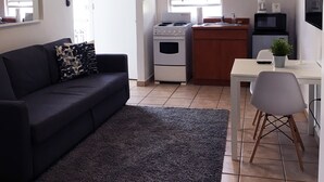 Ett kompakt bostadsutrymme med ett litet kök, en soffa, ett matbord och en TV.