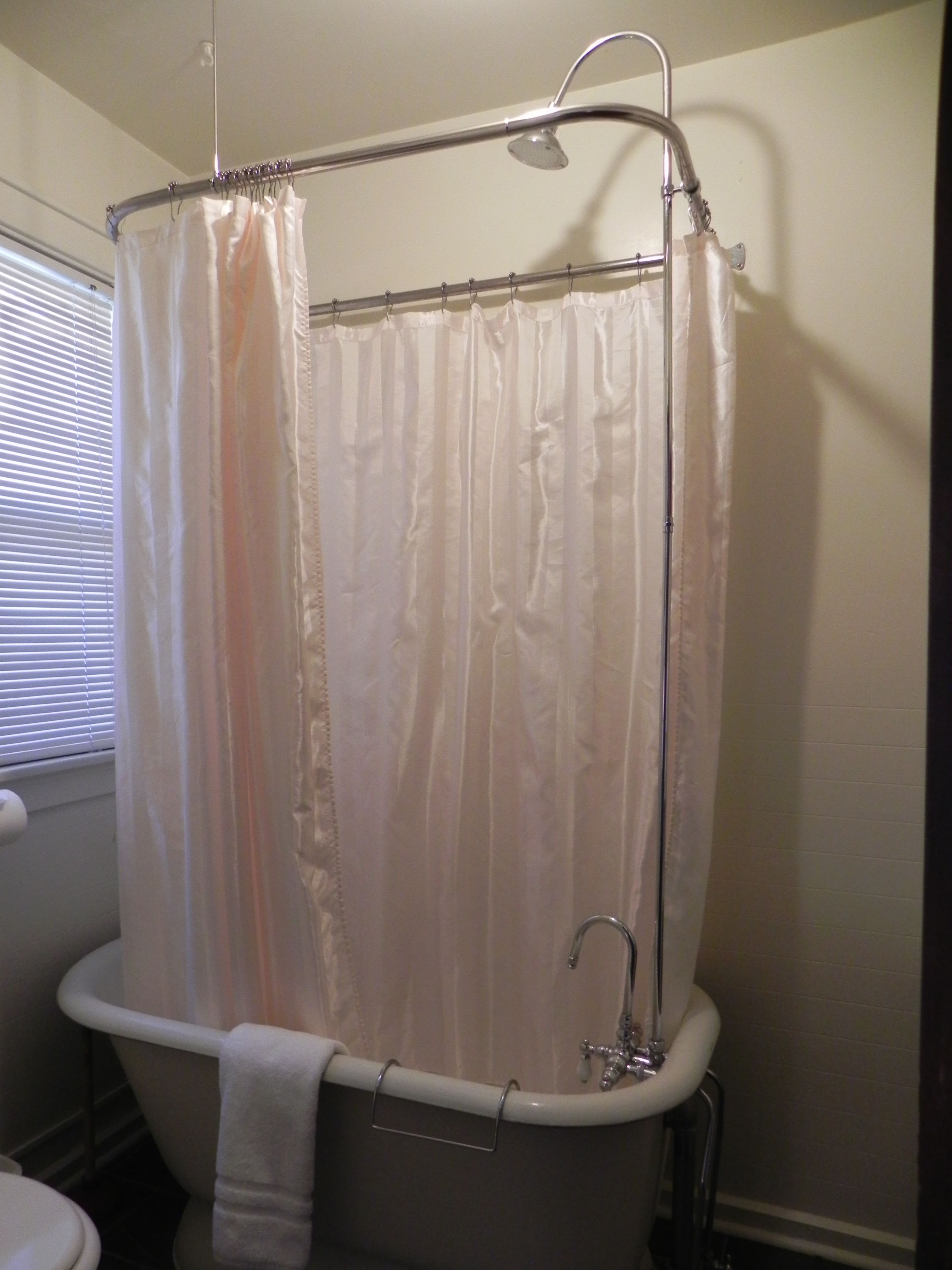 A bathroom with a bathtub, a shower curtain, and a towel hanging on the tub.