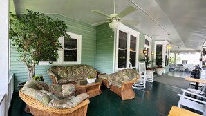 A covered porch with wicker furniture, a ceiling fan, and potted plants. - Vine Cottage Inn (Hot Springs)