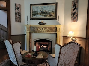 A cozy room with a fireplace, framed paintings, and a table with candles. - Vine Cottage Inn (Hot Springs)