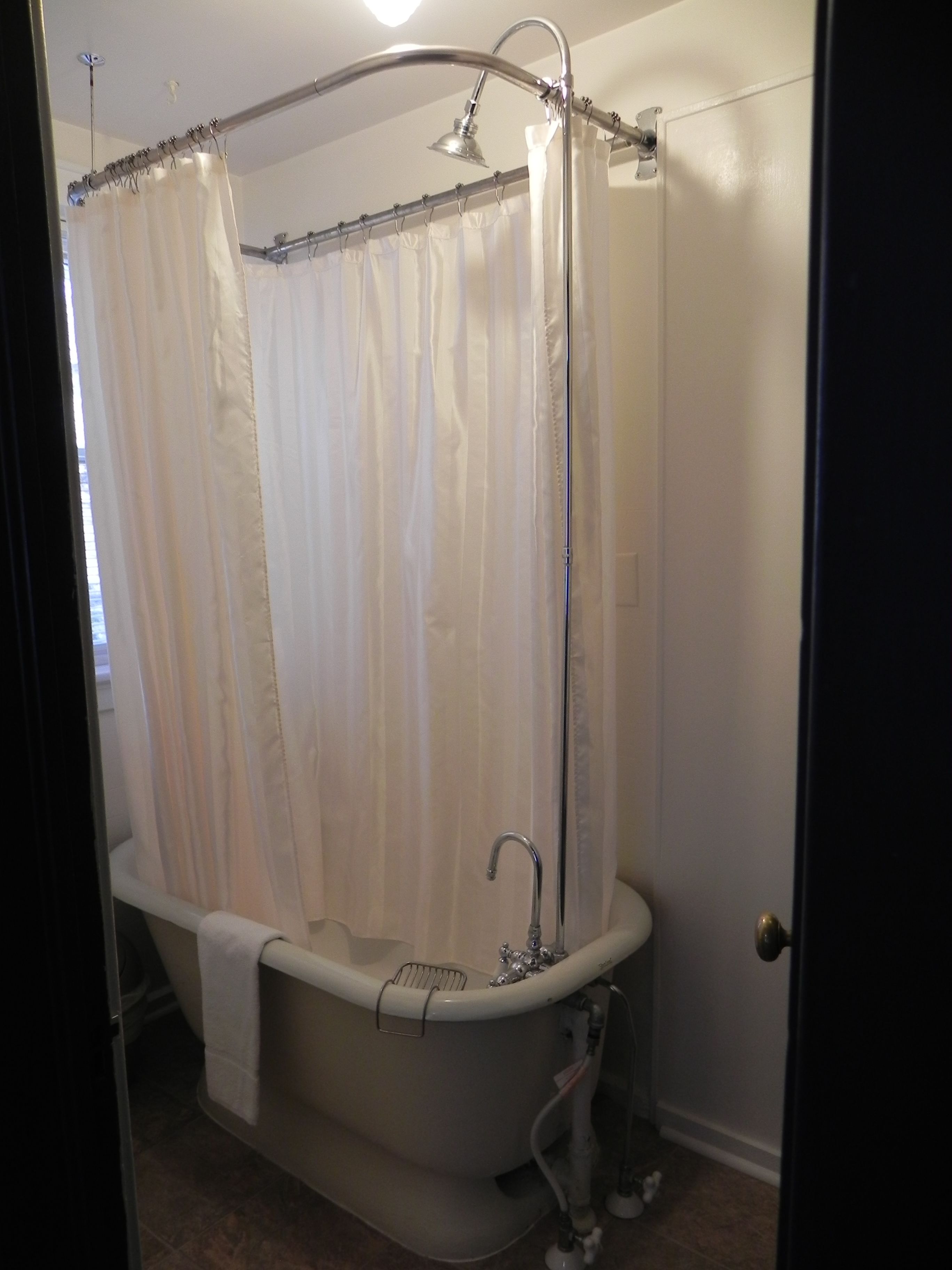 A bathroom with a freestanding bathtub, a shower curtain, and a showerhead.