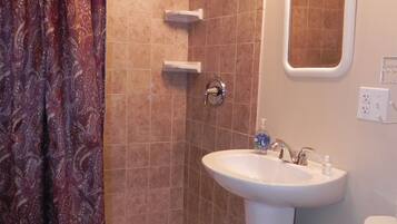 A bathroom with a shower, a sink, and a toilet.