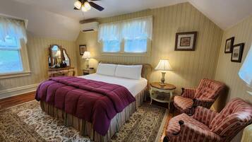 A bedroom with a large bed, two bedside tables, a chair, and a window with curtains.