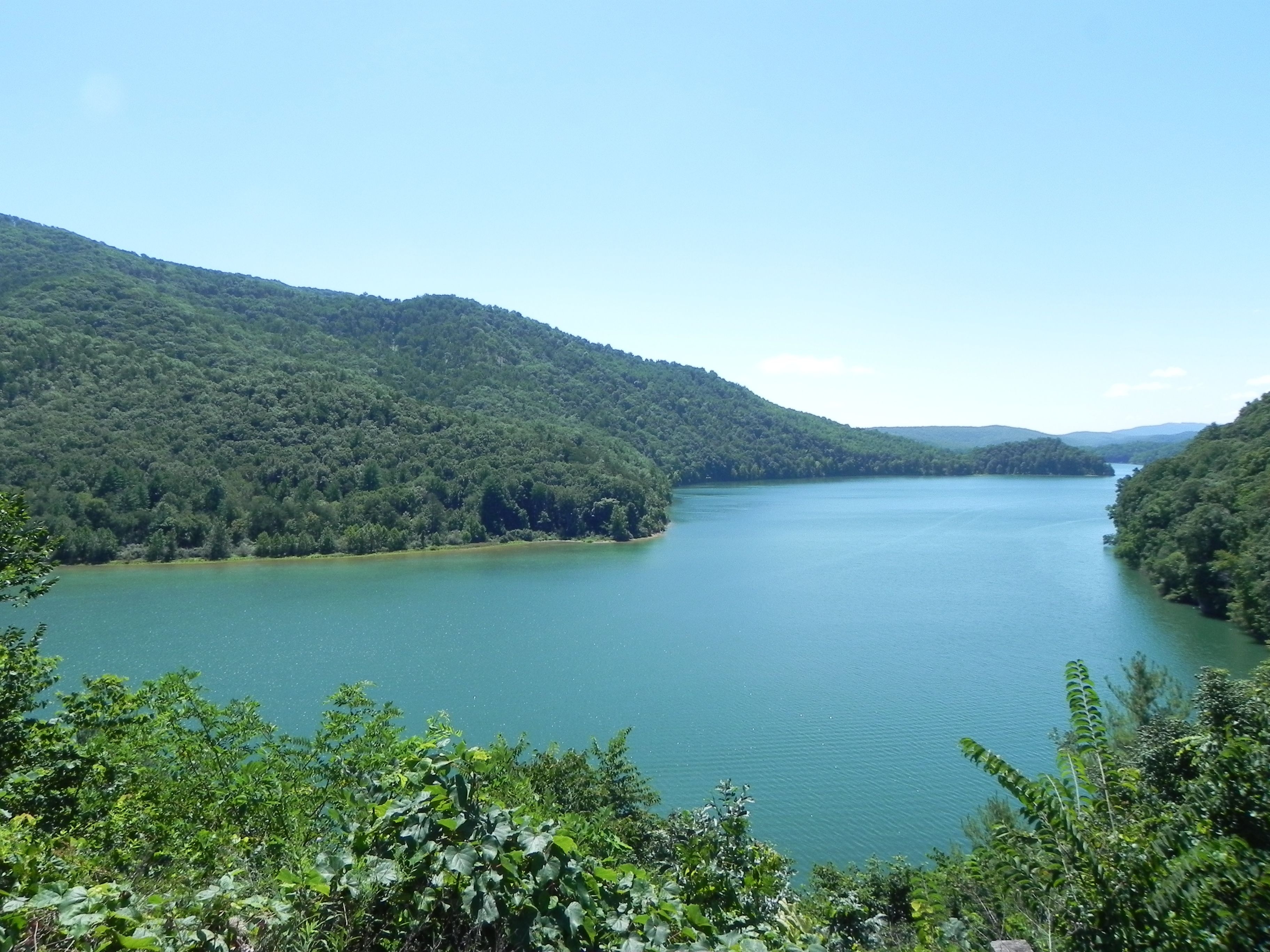 A large lake surrounded by dense forested hills.